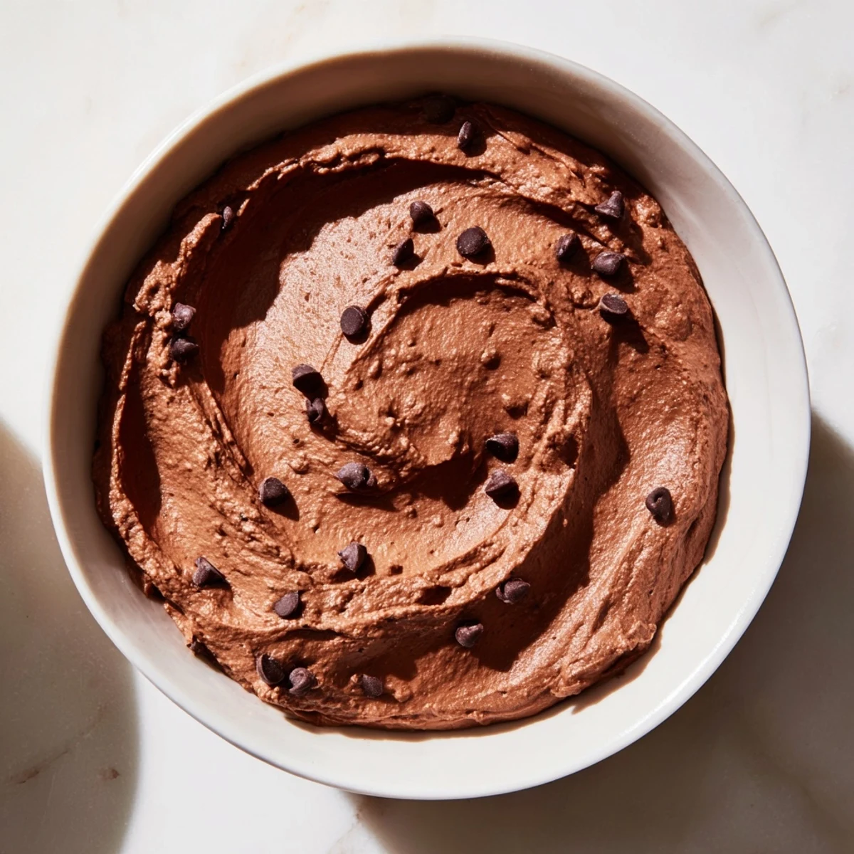 A close-up of creamy Chocolate Hummus, ready for dipping with fresh strawberries on the side.
