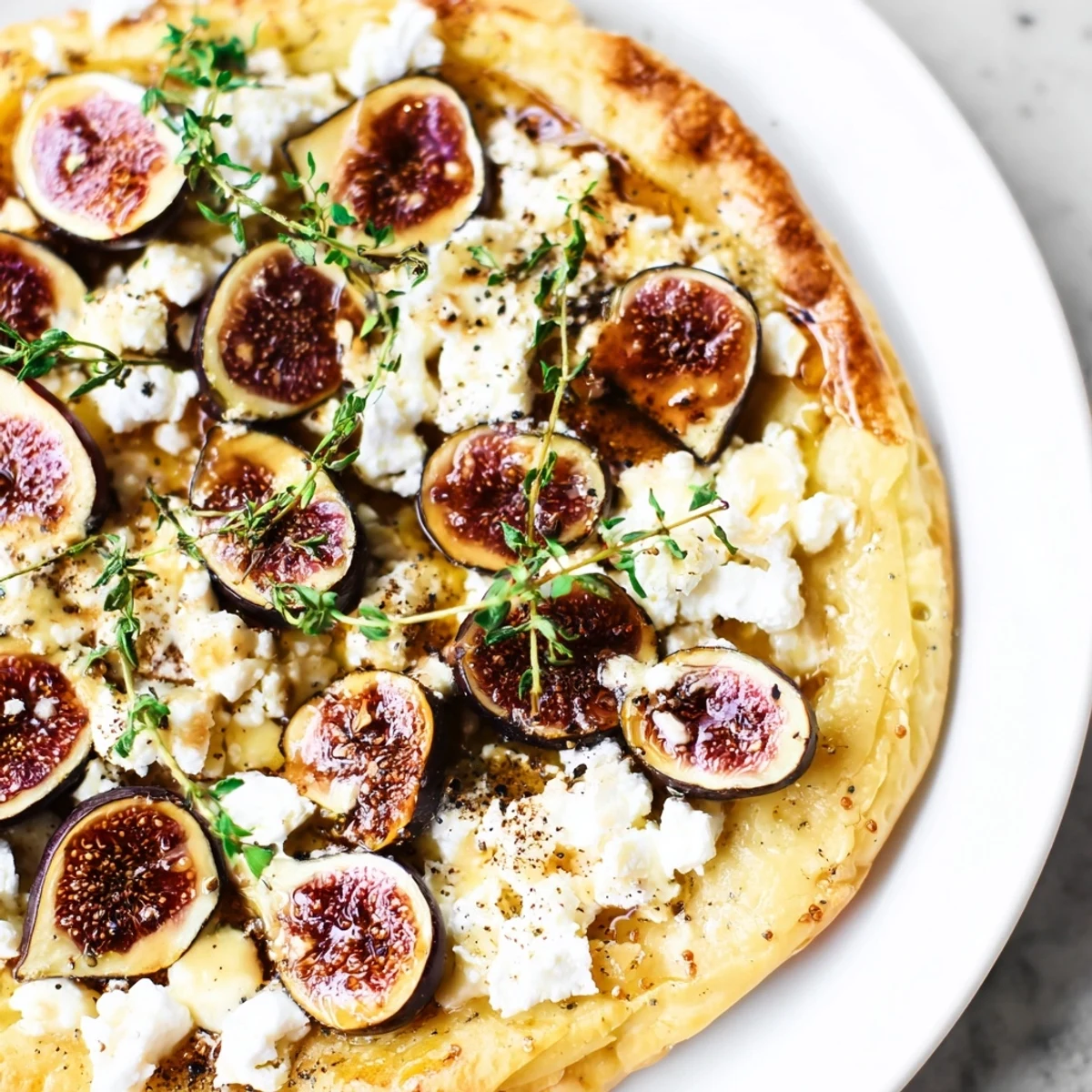 Golden-brown puff pastry truffle pizza with figs, goat cheese, and a honey drizzle for a delightful appetizer.