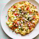 A close-up of a fresh Turkish menemen eggs pizza with a crispy crust, seasoned with parsley.