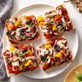 Close-up of baked Rice Cake Pizza Squares, topped with vibrant veggies and cheese, steaming slightly.