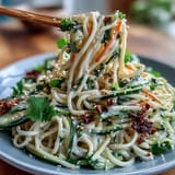 Cold sesame noodle bowl with cucumber, vibrant veggies, and sesame sauce in a colorful, chilled dish.