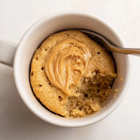 Warm, fluffy 2-Minute Peanut Butter Mug Cake melting in a mug, perfect for quick dessert cravings.