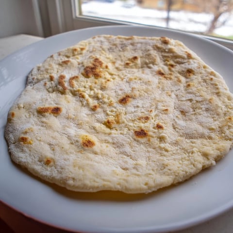 Golden cottage cheese flatbread, lightly browned from pan-frying, ready to be served warm.