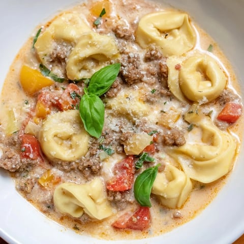Steaming bowl of Tortellini Beef Soup, garnished with Parmesan and fresh basil, ready to enjoy.
