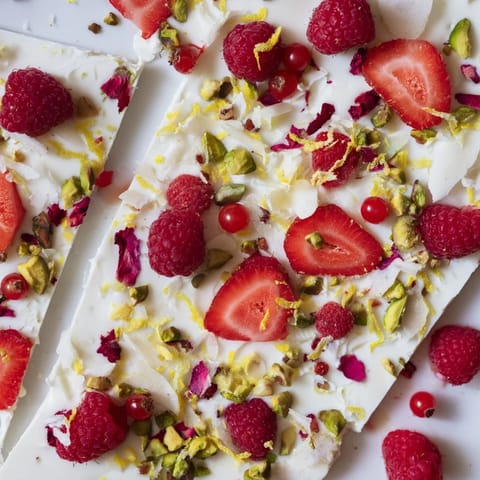 Creamy frozen yogurt bark with a medley of fresh red berries, drizzled with honey, and crunchy nuts.