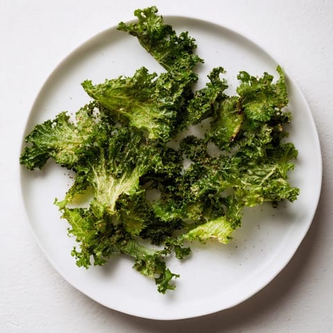 Close-up of perfectly seasoned oven-baked kale chips, a healthy vegan snack with a satisfying crunch.
