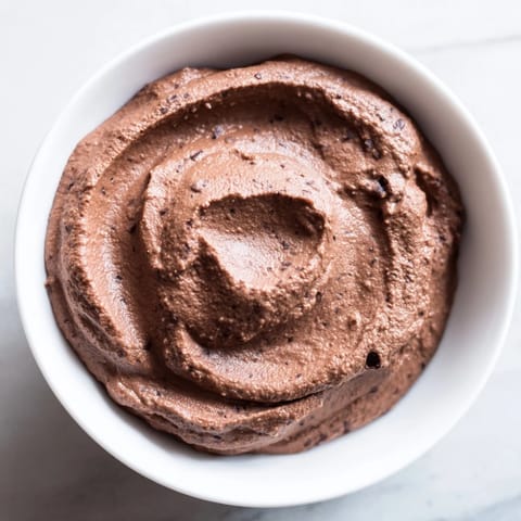 This velvety smooth Chocolate Hummus is swirled in a bowl, perfect for a decadent, healthy dessert.