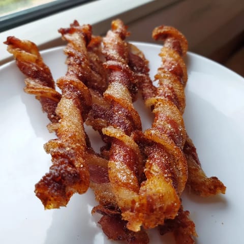 Golden-brown Spiced Bacon Twists glisten on a wire rack, their caramelized cinnamon-sugar coating inviting brunch cravings.  