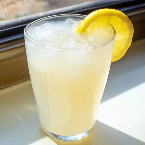 Creamy lemonade recipe served in a clear pitcher beside sliced lemons and ice, perfect for summer.  