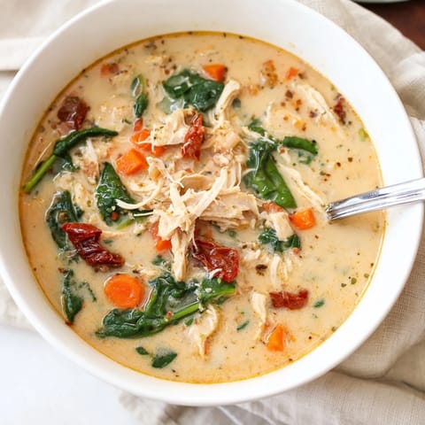 Creamy Tuscan Chicken Soup served in a rustic white bowl, garnished with fresh herbs and a slice of crusty bread.  