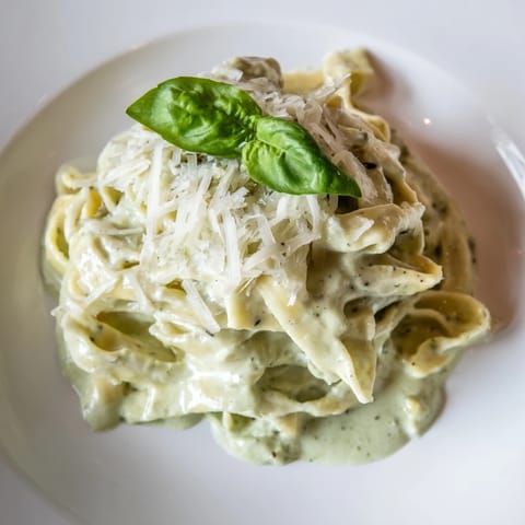 A close-up view of Creamy Green Pea Alfredo pasta featuring sweet peas blended into a rich, velvety sauce topped with cracked black pepper.