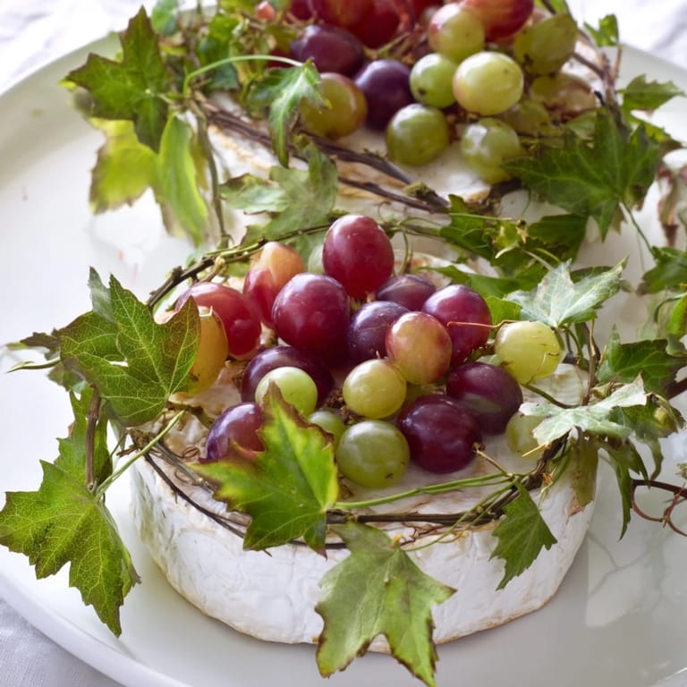 A beautiful Rustic Vineyard cheese wheel, surrounded by grapes and vines, ready for serving guests.