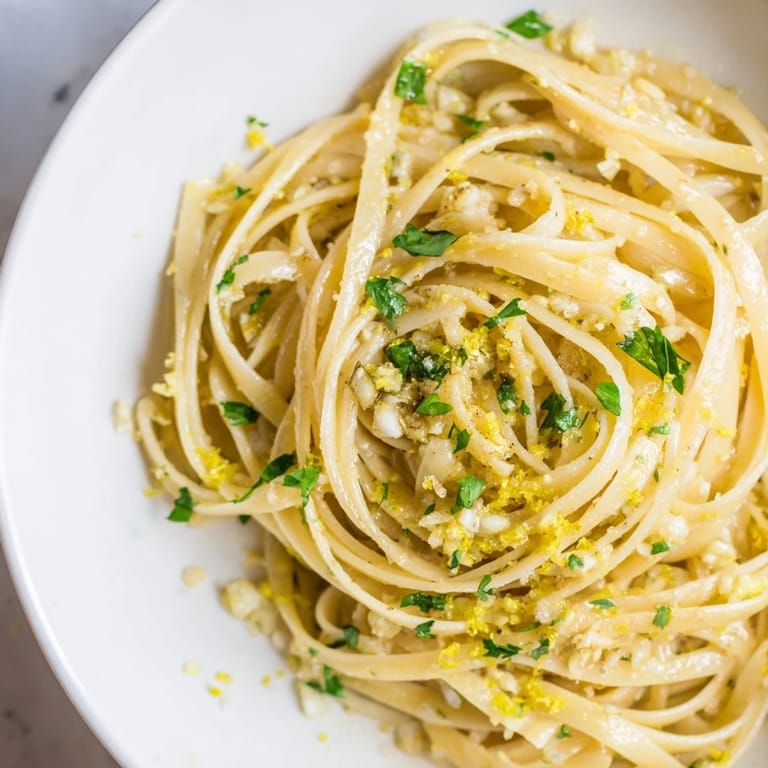 A close-up of creamy Garlic Butter Linguine, perfectly coated, with a sprinkle of Parmesan and lemon zest.