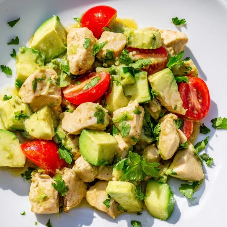 Healthy Avocado Chicken Salad combining tender shredded chicken, ripe avocado, red onion, and herbs, creating a refreshing and creamy texture.