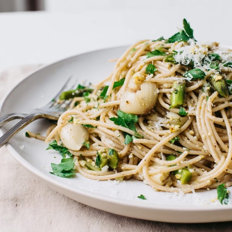 A vibrant serving of Roasted Garlic & Asparagus Pasta on a spring table, with lemon zest and optional red pepper flakes.